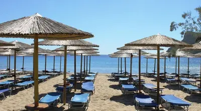 a beach with chairs and umbrellas and the ocean at Villa Clotho in Porto Rafti