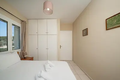 a bedroom with a white bed and a window at Villa Clotho in Porto Rafti
