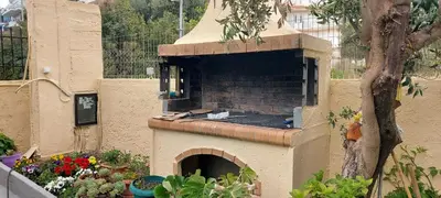 a bird sitting on top of a brick oven at Denis house in Artemida