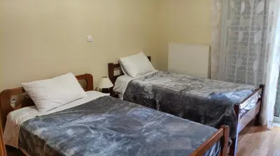 a bedroom with two beds and a table with a lamp at Denis house in Artemida