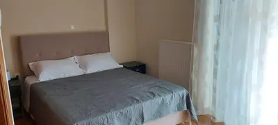 a bedroom with a bed with a gray blanket and a window at Denis house in Artemida
