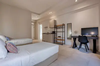 a bedroom with a bed and a desk with a computer at Saronis Suites in Saronida