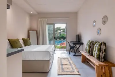 a bedroom with a bed and a bench and a patio at Saronis Suites in Saronida