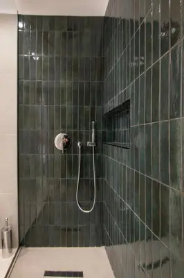 a green tiled bathroom with a shower and a sink at Mythodea Athens Suites in Athens