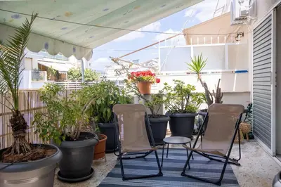 a balcony with chairs and potted plants on it at The House of Praxithea for 6 by Filos Inc in Athens