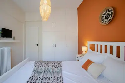 a bedroom with a white bed with an orange wall at The House of Praxithea for 6 by Filos Inc in Athens
