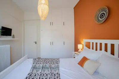 a bedroom with a white bed with an orange wall at The House of Praxithea for 6 by Filos Inc in Athens