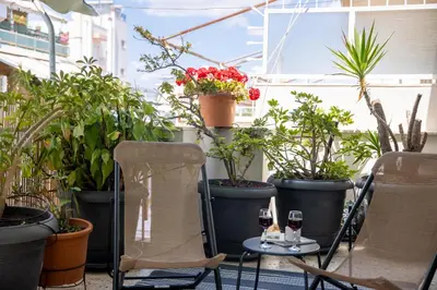 a patio with two glasses of wine and plants at The House of Praxithea for 6 by Filos Inc in Athens