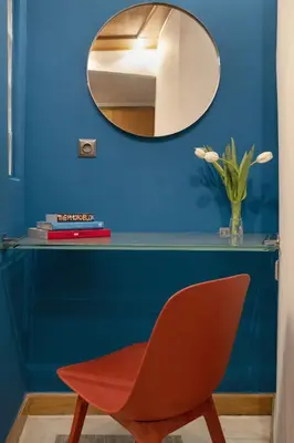 a red chair in front of a blue wall with a mirror at Vibrant apartment in Kolonaki area in Athens