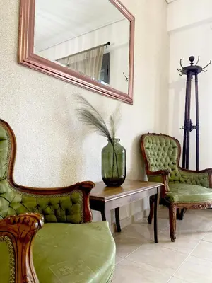 a living room with two chairs and a table with a mirror at Cleo in Spáta