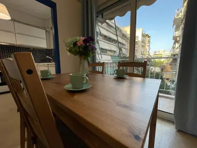 a wooden table with chairs and a vase with flowers on it at Traveller's Choice Attiki in Athens