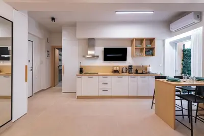 a kitchen with white cabinets and a tv on the wall at Feel like home in Athens