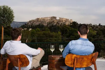 two men sitting at a table with glasses of wine at Visum Acropol ,3BR - Private Terrace-Jacuzzi - Amazing View in Athens