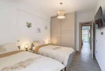 a bedroom with two beds and a flat screen tv at stylish zografou apartement in Athens