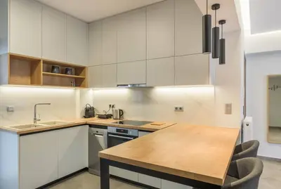 a kitchen with white cabinets and a wooden table at stylish zografou apartement in Athens