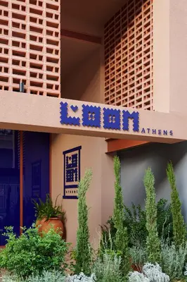 a sign on the side of a building with plants at LOOM ATHENS in Athens