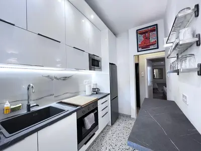 a kitchen with white cabinets and a black sink at James - 2BR in the Heart of Ancient Athens in Athens