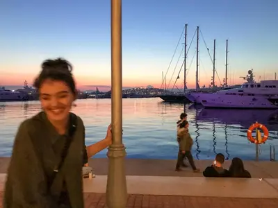 a woman standing next to a marina with a boat at Athens Stylish apt next to the beach and port in Athens