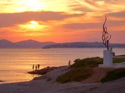 a group of people standing on a beach at sunset at Athens Stylish apt next to the beach and port in Athens