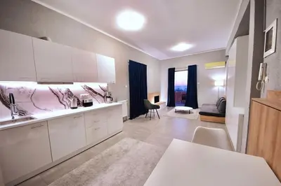 a kitchen with white cabinets and a living room at Athens Riviera Modern Penthouse with Sea View in Athens