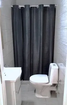 a bathroom with a toilet and a black shower curtain at Athens Riviera Modern Penthouse with Sea View in Athens