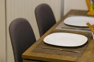 two white plates on a wooden table with chairs at SOKOS Residence, 3' walk from Neos Kosmos Metro in Athens