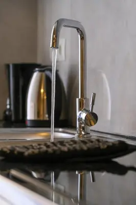 a kitchen sink with water running from a faucet at SOKOS Residence, 3' walk from Neos Kosmos Metro in Athens