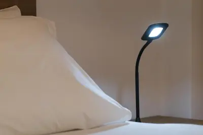 a lamp next to a bed with a white pillow at SOKOS Residence, 3' walk from Neos Kosmos Metro in Athens