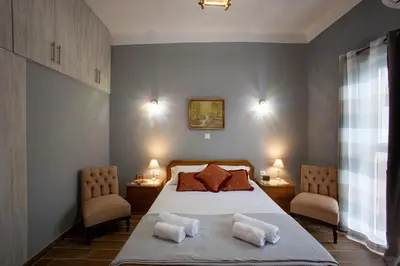 a bedroom with a large bed with two chairs at Danaï house in Athens