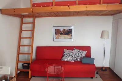 a red couch in a room with a loft bed at Rooftop Athens Central Studio in Athens