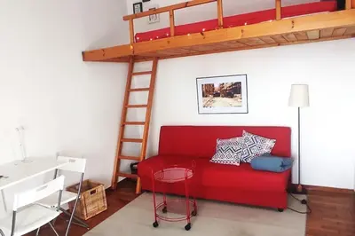a red couch in a room with a loft bed at Rooftop Athens Central Studio in Athens