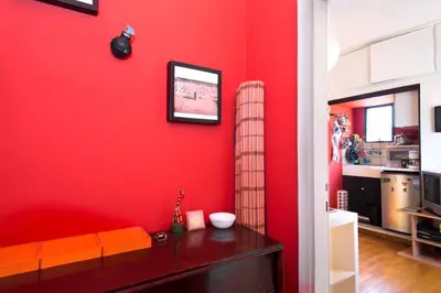 a room with a red wall with a bench and a tv at Rooftop Athens Central Studio in Athens