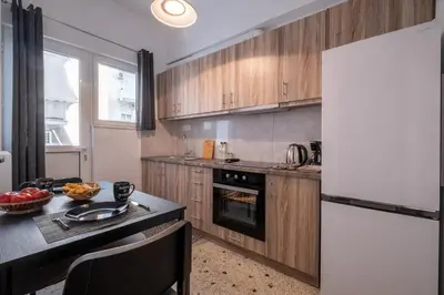 a kitchen with wooden cabinets and a white refrigerator at SOKOS Residence, 1' walk from Aghios Ioannis Metro in Athens
