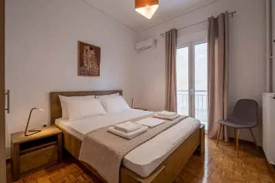 a bedroom with a bed with a chair and a window at SOKOS Residence, 1' walk from Aghios Ioannis Metro in Athens