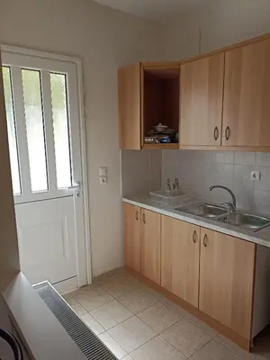 a kitchen with wooden cabinets and a sink and a door at Airport city center 2 in Spáta