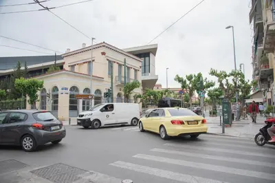 a busy city street with cars on a crosswalk at Harmony apartment next to the Acropolis museum in Athens