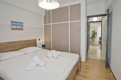 a bedroom with a white bed with towels on it at Blue Dream Modern Piraeus Apt, Walk to Beach in Piraeus