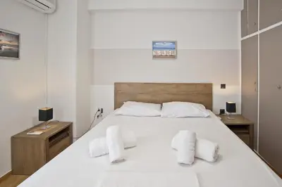 a bedroom with a large white bed with two white towels at Blue Dream Modern Piraeus Apt, Walk to Beach in Piraeus