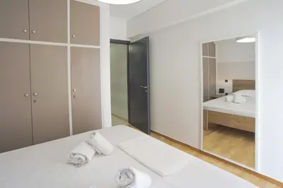 a white bedroom with a bed and a mirror at Blue Dream Modern Piraeus Apt, Walk to Beach in Piraeus