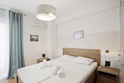 a bedroom with a large white bed and a window at Blue Dream Modern Piraeus Apt, Walk to Beach in Piraeus