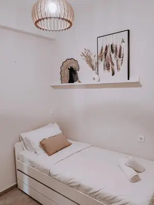 a white bedroom with a bed and a chandelier at Bohemian Apartment in Central Athens in Athens