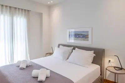 a white bedroom with a bed with towels on it at The Urban Nest Design 1BR in Trendy Kerameikos in Athens