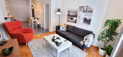 a living room with a black couch and a red chair at Cozy & modern apartment near Panathenaic Stadium in Athens