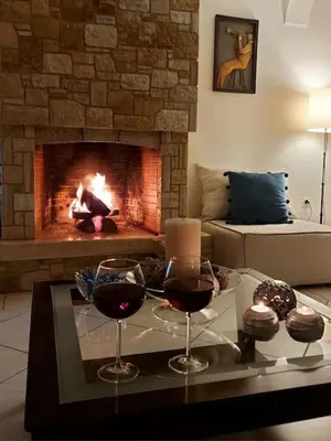 two glasses of wine on a table in front of a fireplace at Inspiration Alimos Getaway, close to the beach in Athens