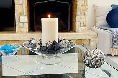 a candle on a glass table in front of a fireplace at Inspiration Alimos Getaway, close to the beach in Athens