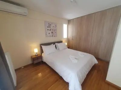 a bedroom with a white bed with a wooden wall at Lux & Style 75sqm with Private Parking in Athens in Athens