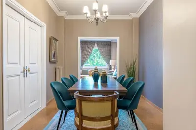 a dining room with a wooden table and green chairs at Exclusive Acropolis 4BDR Large Residence in Athens