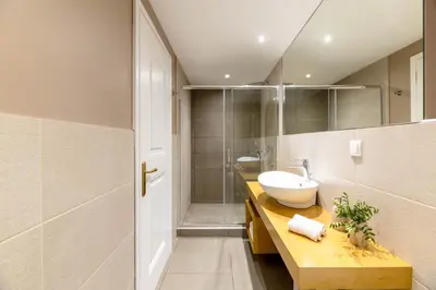 a bathroom with a sink and a glass shower at Exclusive Acropolis 4BDR Large Residence in Athens