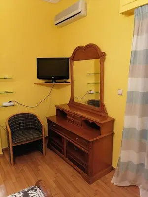 a room with a dresser with a mirror and a tv at Дом для гостей in Athens