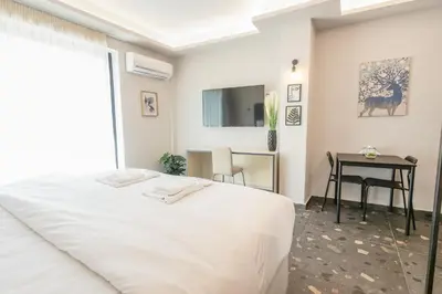 a white bedroom with a bed and a table at City Life Athens Apartments in Athens